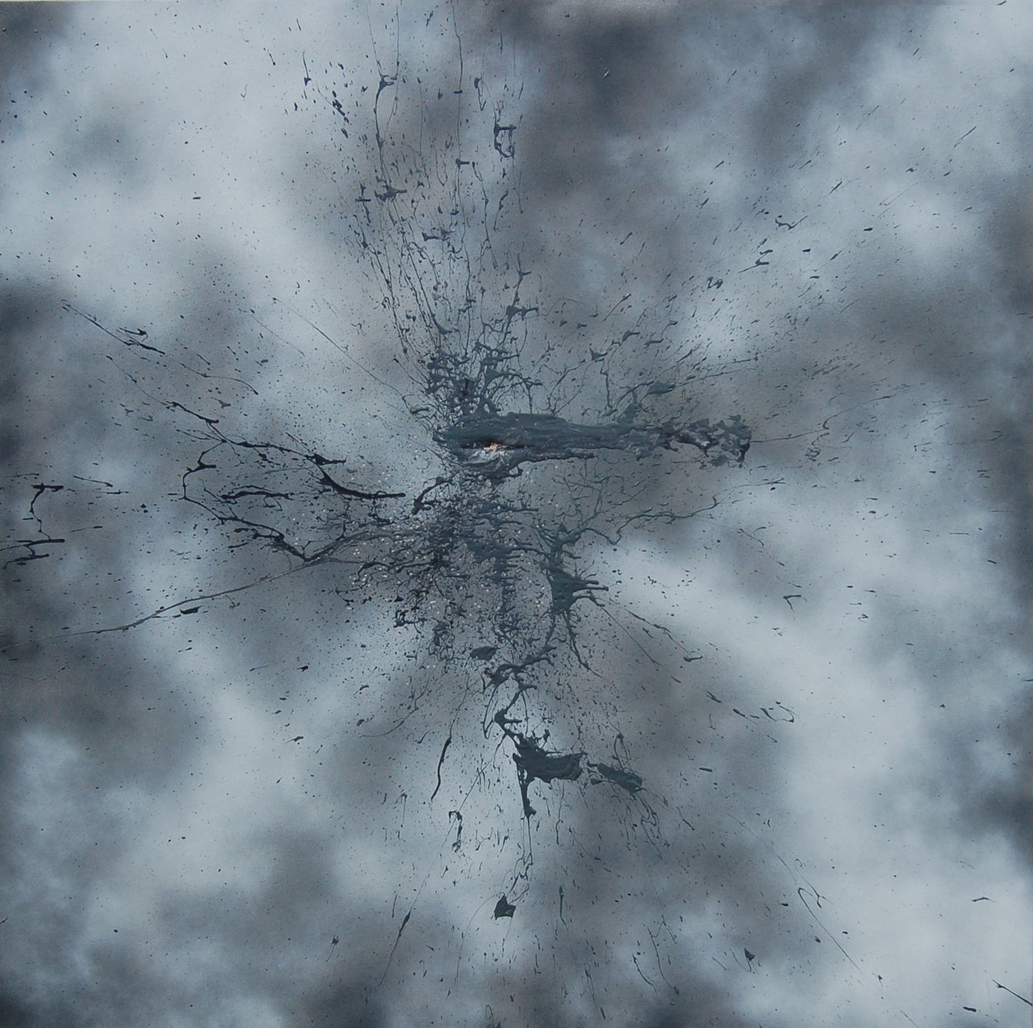 A black mark applied with a shotgun on a sprayed grey and white background.