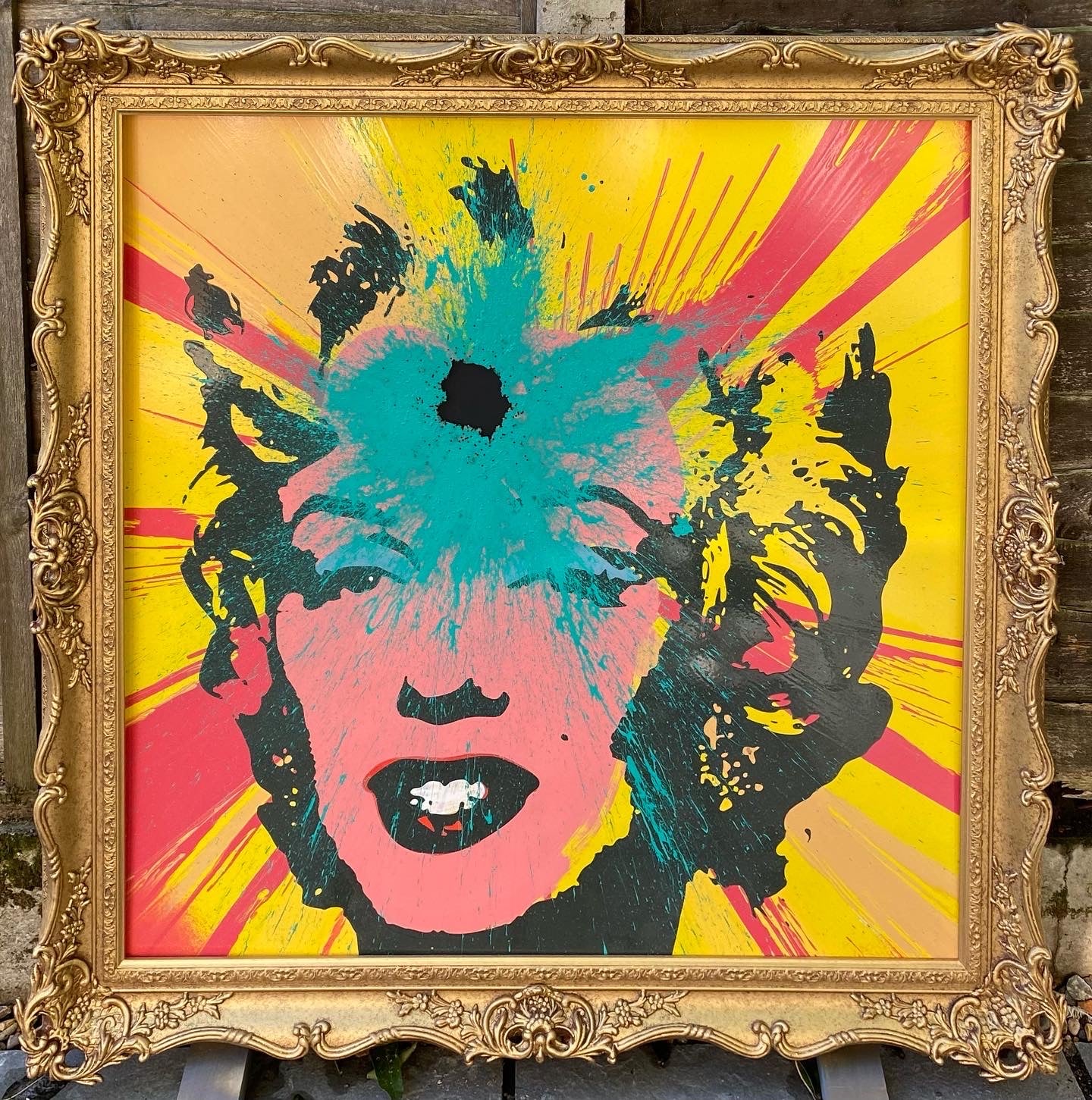 Andy Warhol’s image of Marilyn on a red and yellow spin painting wish a splash of turquoise applied with a shotgun.